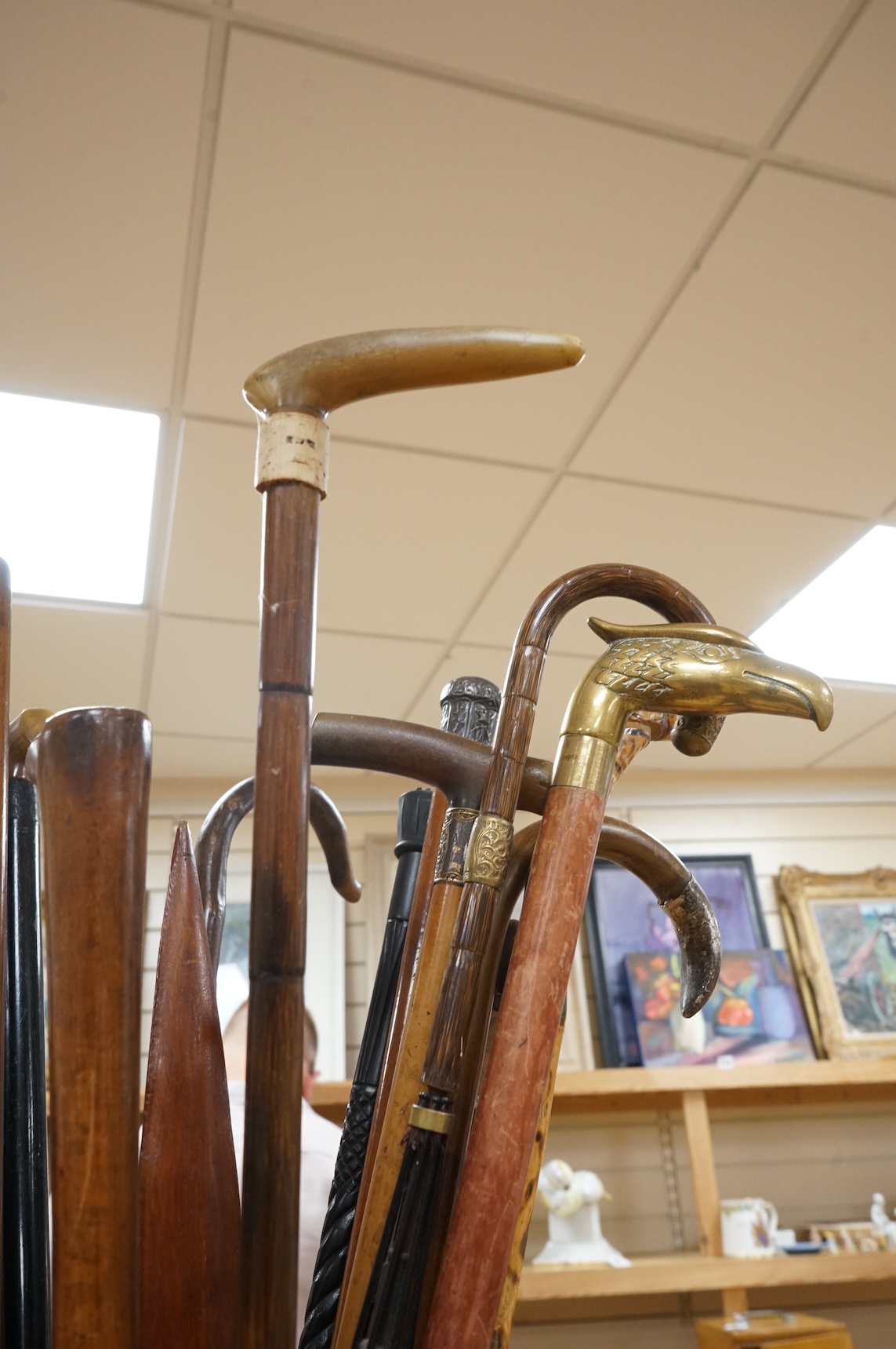 A collection of various walking sticks, some silver mounted, an umbrella with bamboo handle and a brass stick stand, stick stand 45cm high